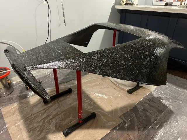Freestanding carbon roof shell on workshop supports.